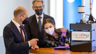 Eine Schülerin erklärt Bundeskanzler Olaf Scholz und D21-Präsident Hannes Schwaderer an ihrem Stand ein Funkmodell.