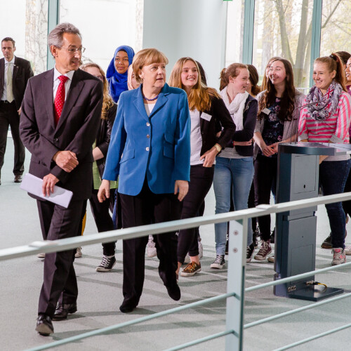 Angela Merkel und Hannes Schwaderer gehen mit einer Gruppe Schülerinnen durch das Bundeskanzleramt.