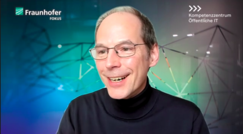 Peter Parycek in einem Videokonferenzfenster mit einem vlaugrünen Hintergrund des Fraunhofer FOKUS