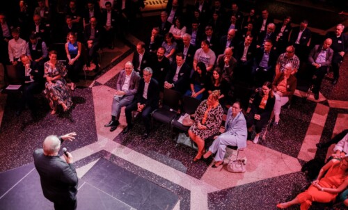 Thomas Langkabel spricht auf der Bühne der D21-Präsidentschaftsübergabe. Rechts im Bild sieht man das Publikum, das ihm aufmerksam und lächelnd zuhört.