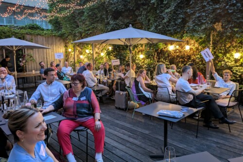 Auf der Terrasse sitzen alle in der Abenddämmerung zusammen und unterhalten sich